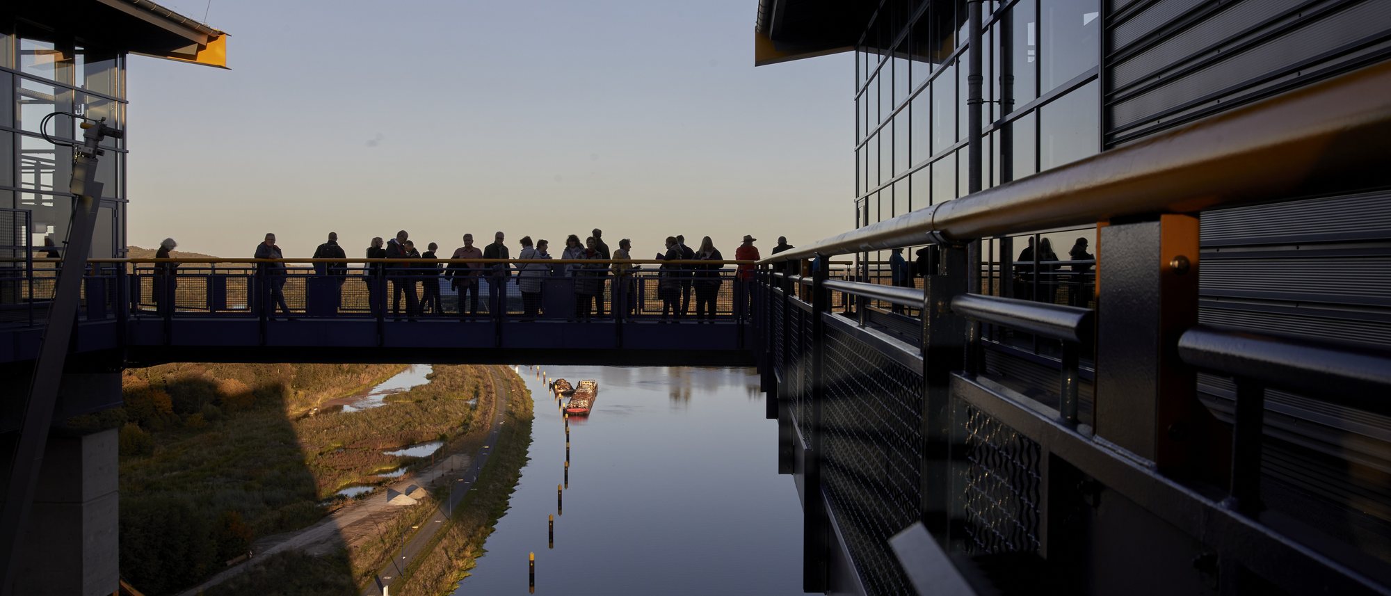 Zuhörer stehen in der Dämmerung auf der Brücke des Neuen Schiffshebewerks Niederfinow, darunter der Kanal in der Auenlandschaft