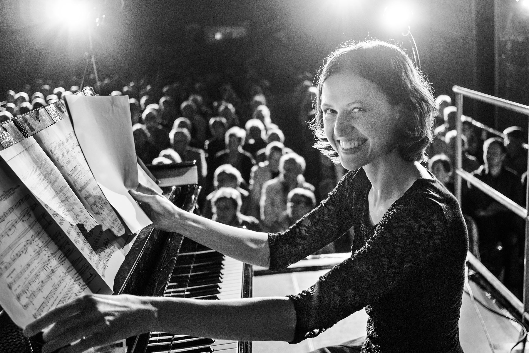 Die Pianistin Alina Pronina lacht am Flügel in die Kamera, hinter ihr das voll besetzte Deck
