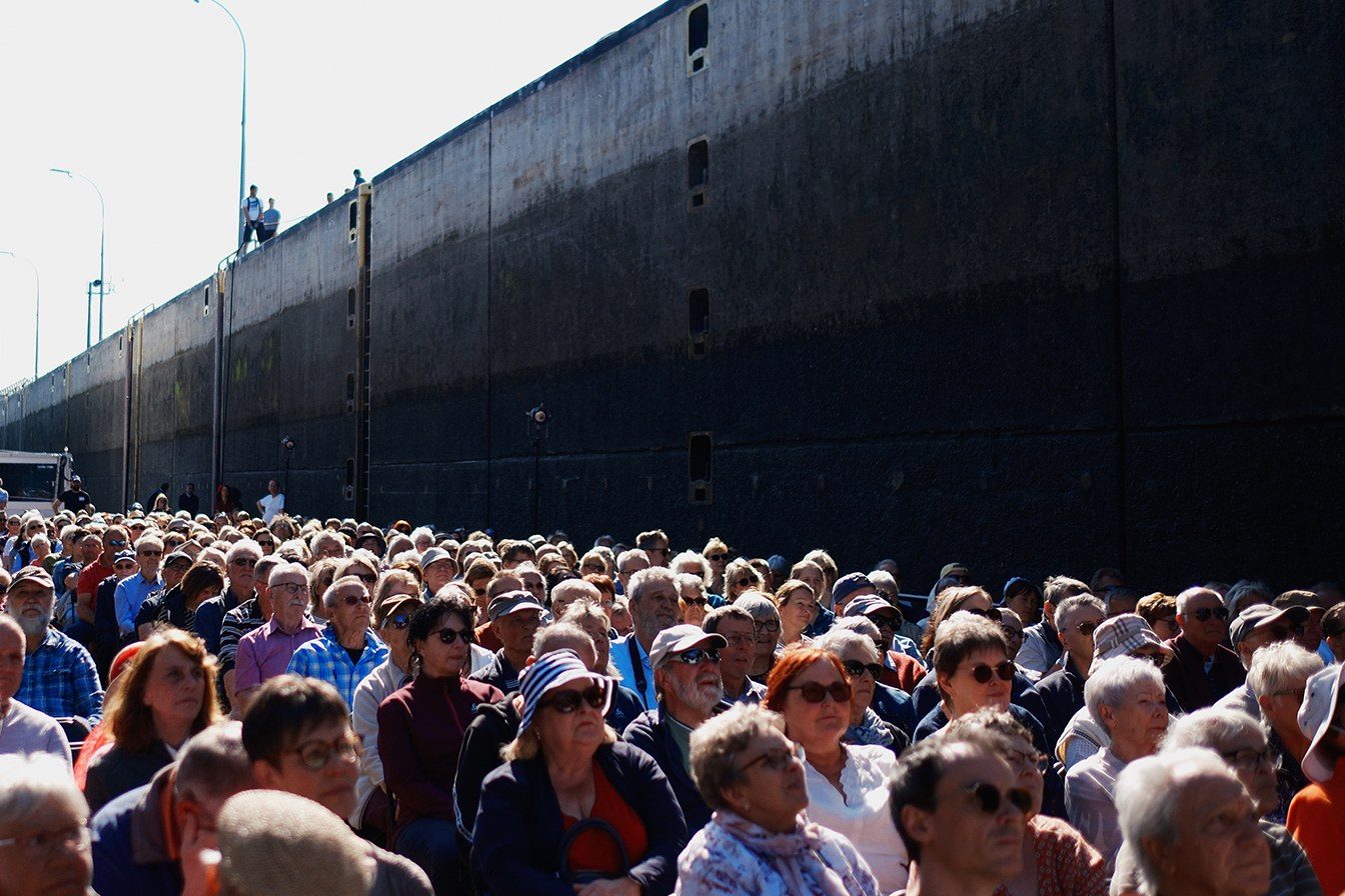 Dicht besetzte Reihen unter der hohen Schleusenwand, das Publikum schaut nach vorn zur Bühne